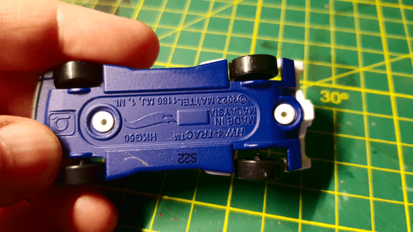 A close up of the bottom of a hot wheels car, showing the metal rivets that will need to be drilled out using a drill or rotary tool/dremel before painting them for use in Gaslands